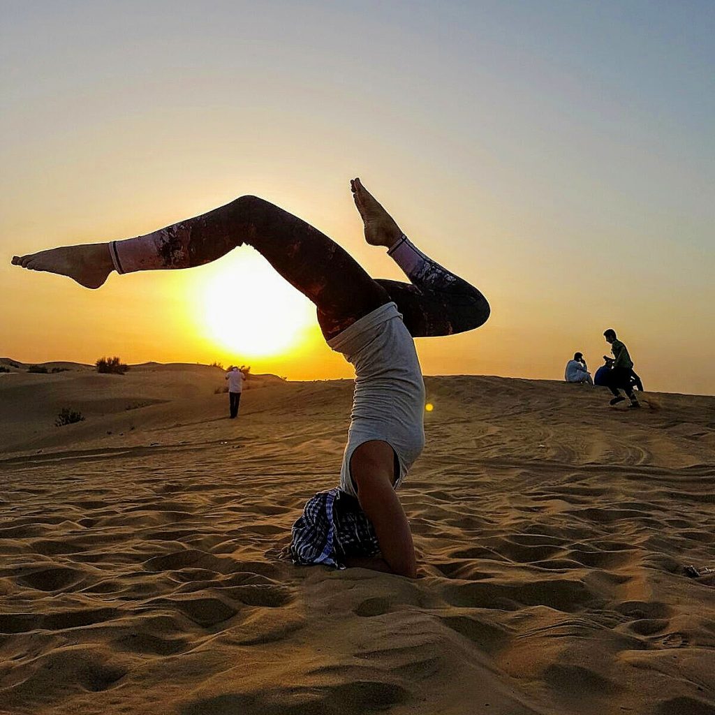 Outdoor yoga practice near the ocean. Young woman practicing Adho Mukha  Vrksasana. Yoga Handstand is an inverted asana. Beautiful asana. Strong  slim body. Yoga retreat. Copy space. Bali Stock Photo